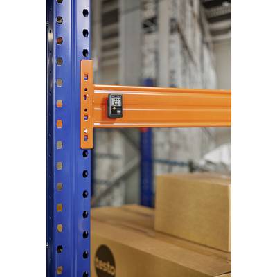 Regal im Lager mit orangefarbenem Balken und digitalem Thermometer, das 23,1 Grad anzeigt. Kartons darunter sind sichtbar.