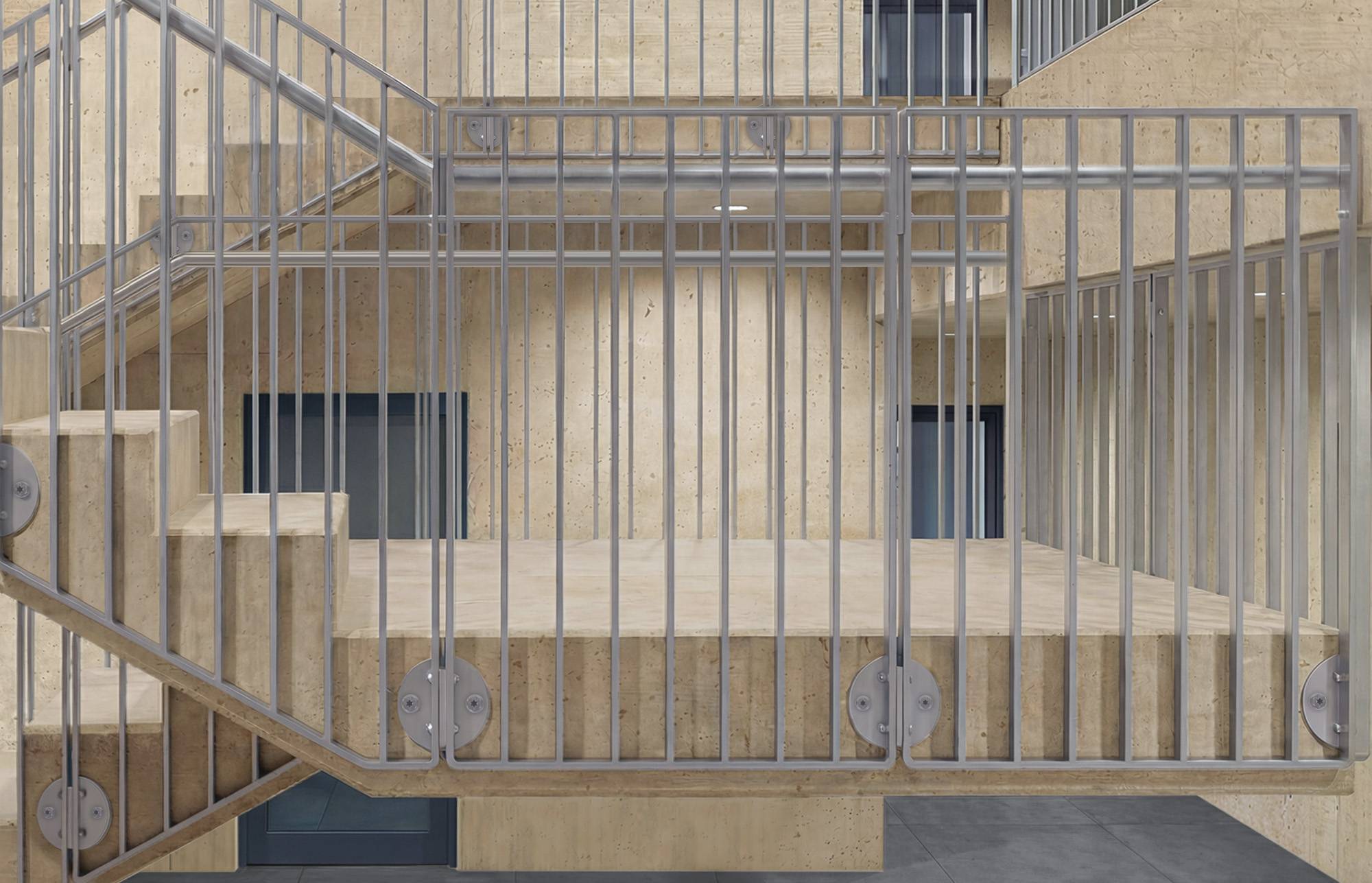 Moderne beige Gebäudefassade mit einem vorspringenden Balkon oder Treppenpodest, das von vertikalen Metallgeländern umschlossen ist, und einer Treppe auf der linken Seite.