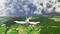 Ein kleines Flugzeug fliegt über eine grüne Landschaft in Richtung einer Landebahn, während am Horizont dunkle Wolken aufziehen.