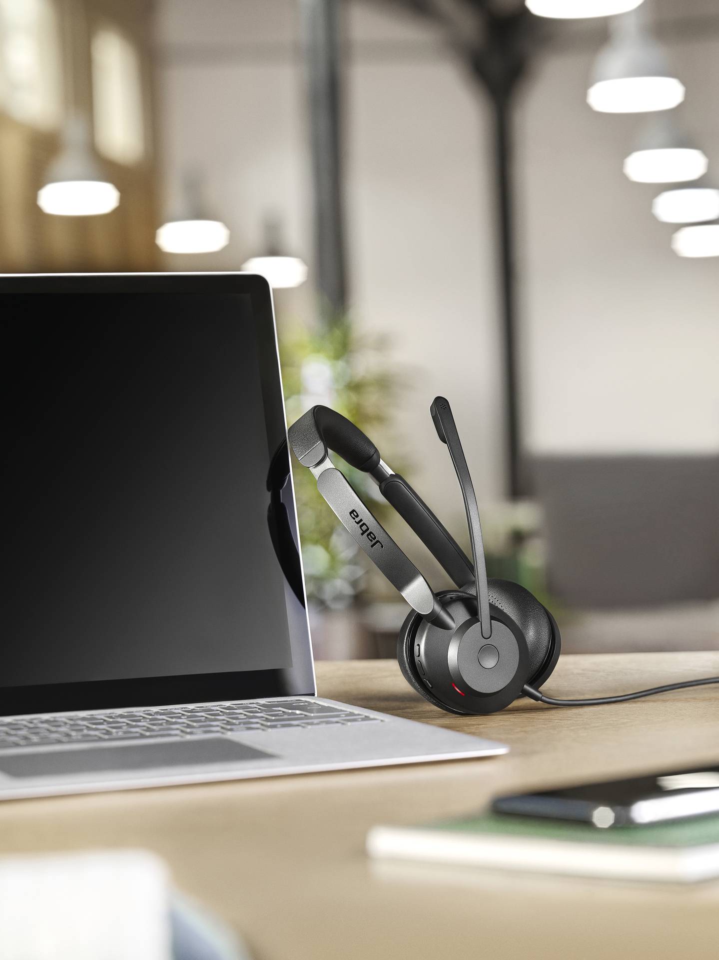 Ein Laptop steht auf einem Schreibtisch. Ein Headset liegt darauf, bereit für Videokonferenzen oder Telefonate.