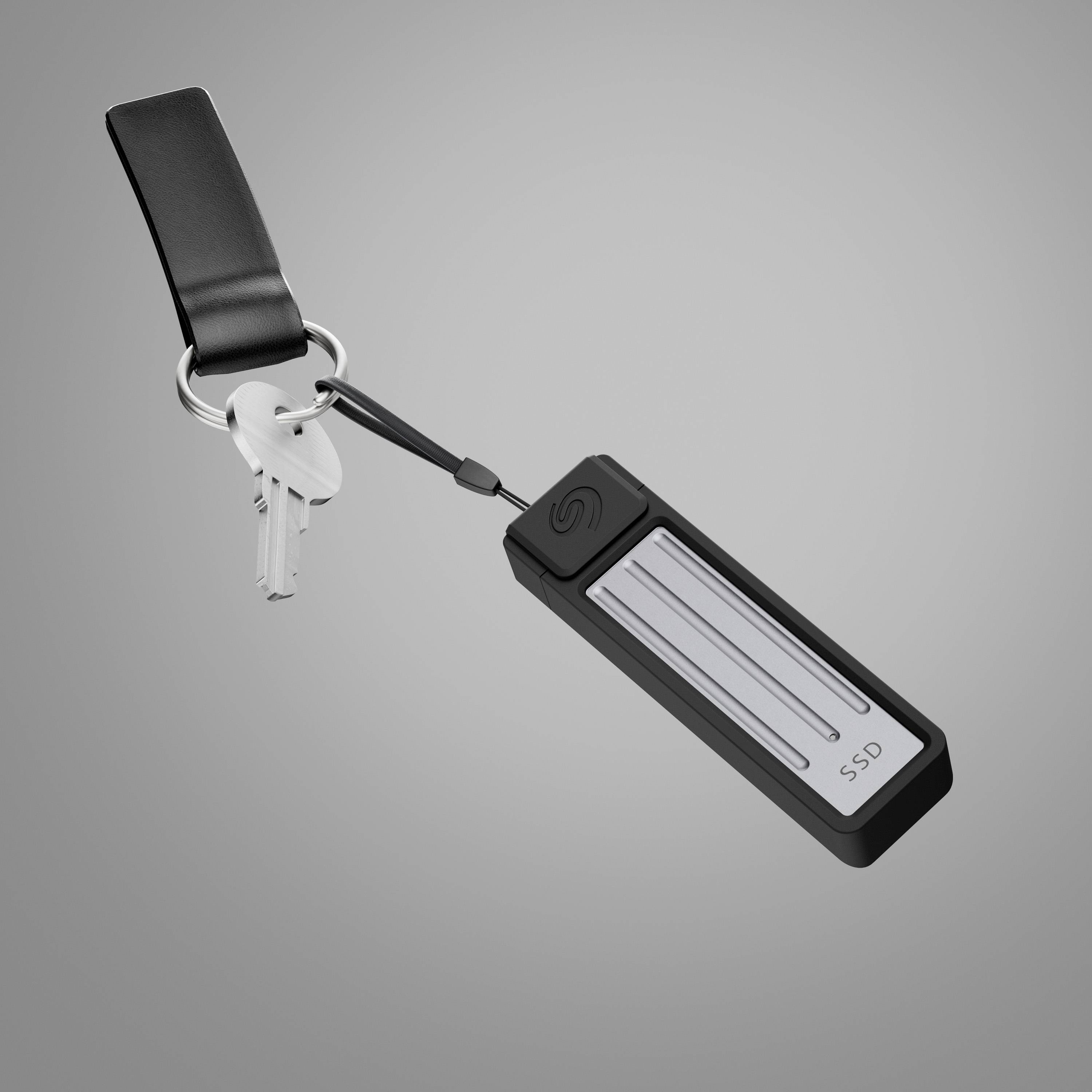 Ein USB-Stick mit der Aufschrift 'SSD' hängt an einem Schlüsselbund mit zwei Schlüsseln. Der Hintergrund ist grau.