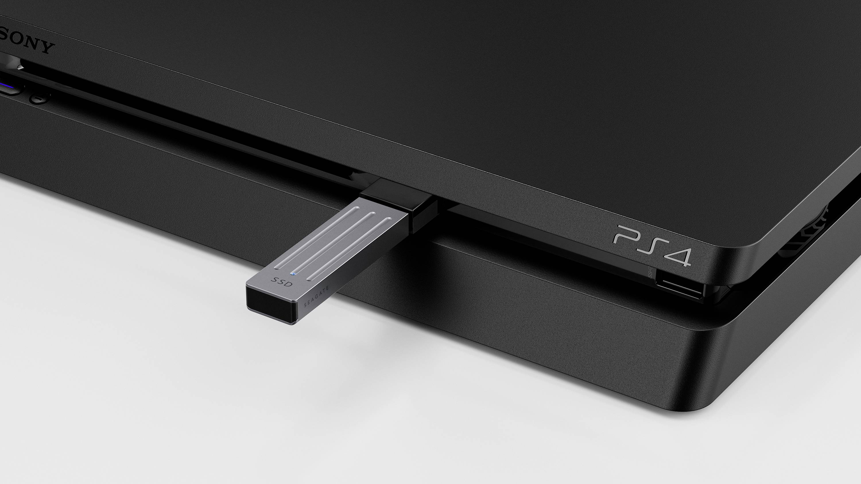 Eine schwarze Spielkonsole mit der Aufschrift 'PS4'. Ein USB-Stick ist in den USB-Anschluss der Konsole eingesteckt.