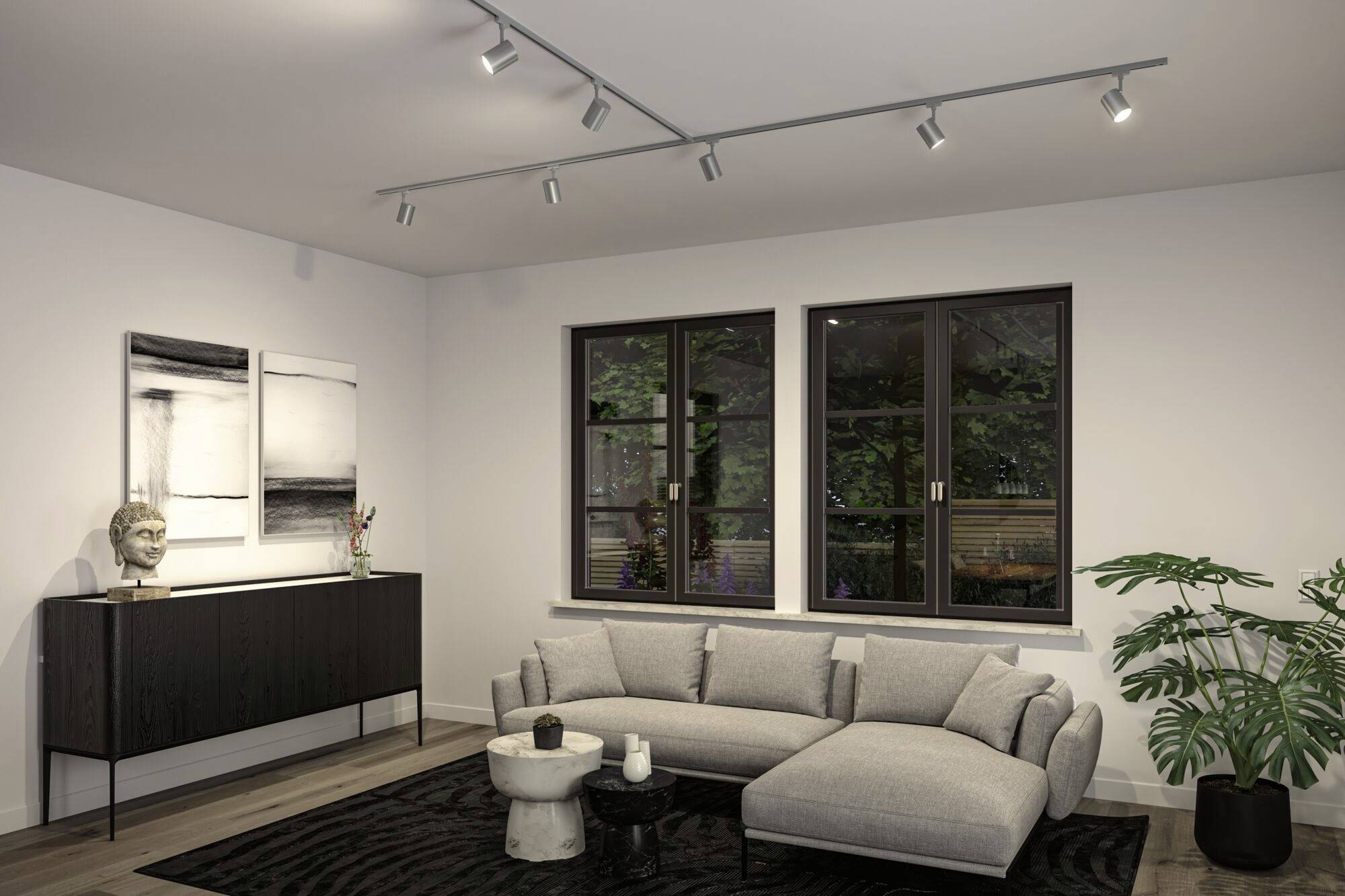 Offenes Wohnzimmer mit grauem Sofa, Couchtischen, Pflanze und Kunstwerken, beleuchtet durch moderne Deckenstrahler.