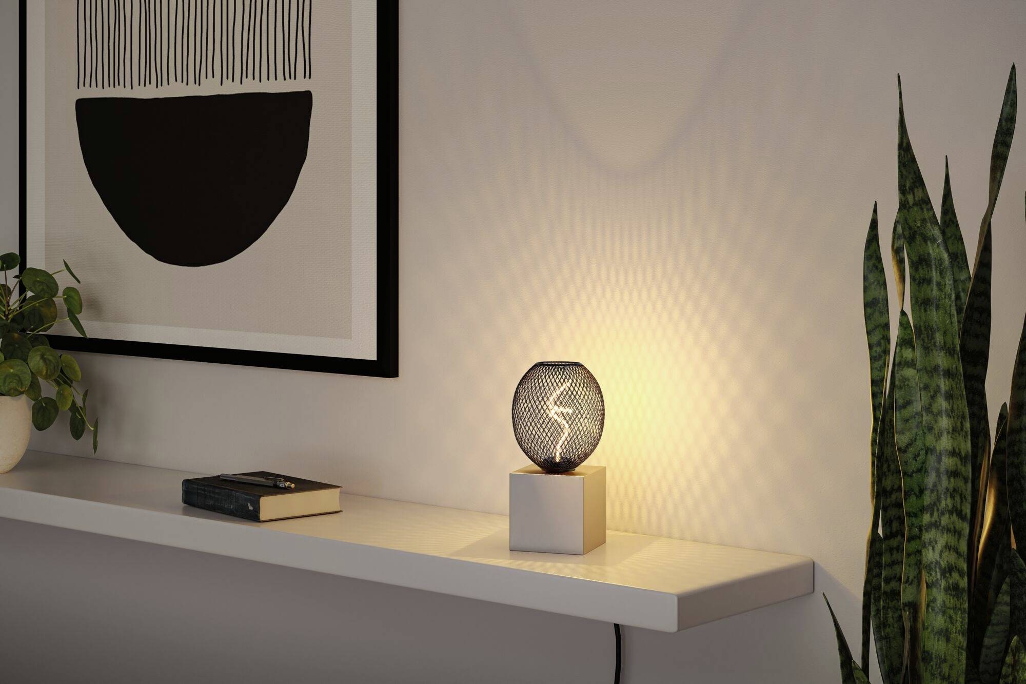 Ein beleuchteter Tisch mit einer kleinen Lampe in der Mitte eines modernen Wohnzimmers, umgeben von Pflanzen und einem Wandbild.