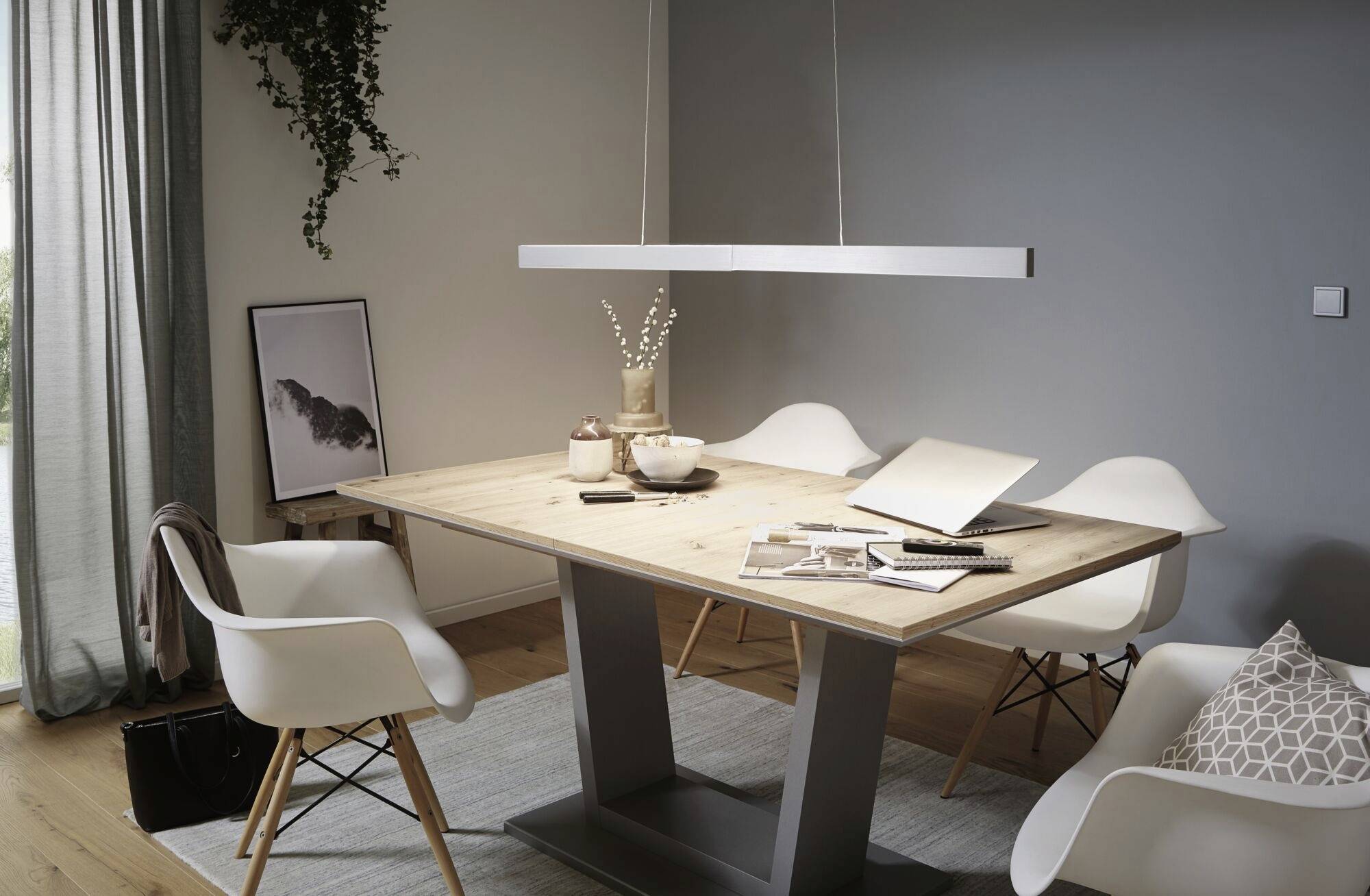Moderner Essbereich mit Holztisch und vier weißen Stühlen; stilvolle Hängelampe; Wandkunst und Pflanzenakzent.