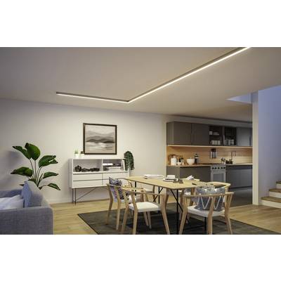 Modernes Wohnzimmer mit Esstisch, Stühlen und grauem Sofa. Offene Küche im Hintergrund. Dezente Beleuchtung und Wandkunst.