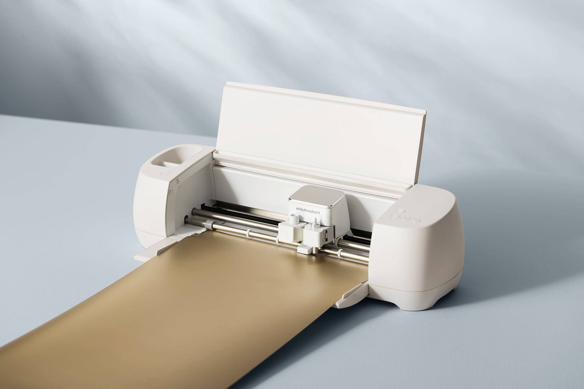 Ein Schneideplotter schneidet ein Blatt goldfarbenes Material. Der Hintergrund ist hellblau.