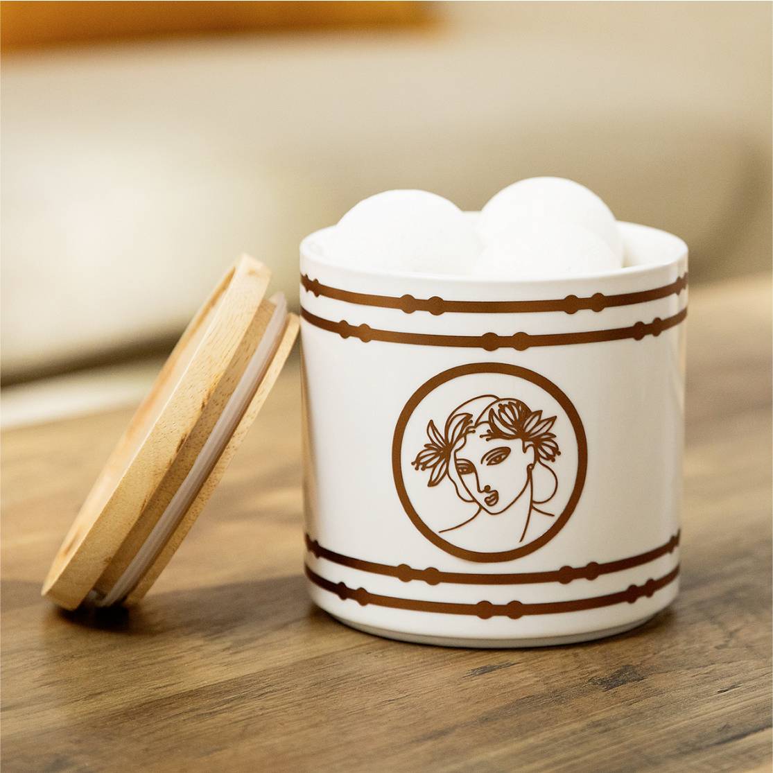 Eine weiße Keramikdose mit braunem Muster und einem antiken Porträt. Der Holzdeckel ist abgenommen.