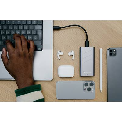 Eine Hand tippt auf einem Laptop. Daneben liegen kabellose Ohrhörer, ein Smartphone, ein Tablet, ein Ladegerät und ein Eingabestift.
