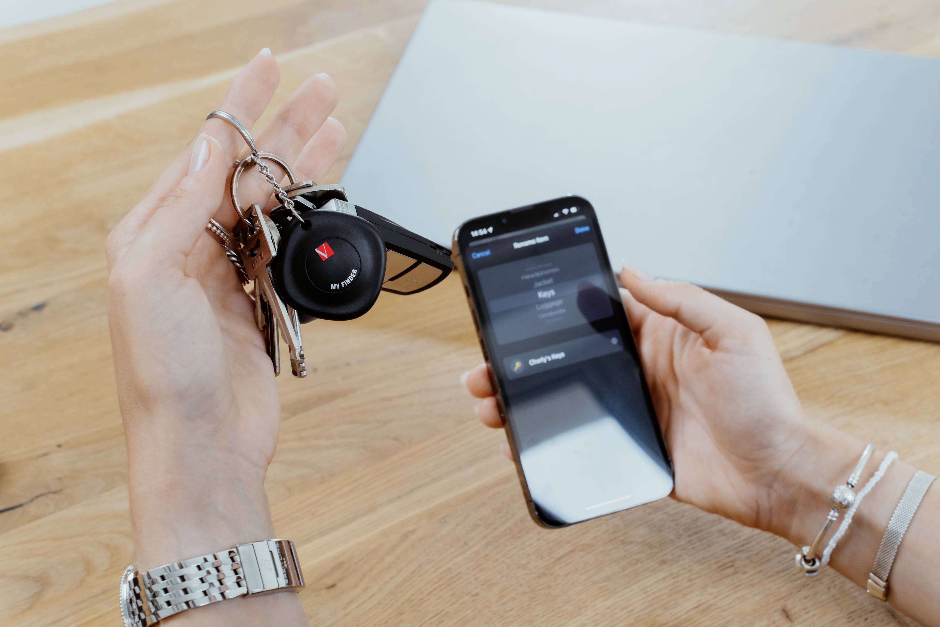 Eine Person hält einen Schlüsselbund mit einem Auto-Fernschlüssel in einer Hand und ein Smartphone in der anderen, auf dem eine App geöffnet ist.