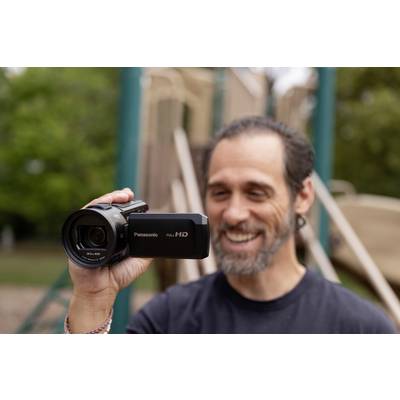Ein Mann filmt im Freien mit einer Panasonic Full HD Videokamera. Im Hintergrund ist ein unscharfer Spielplatz zu sehen.
