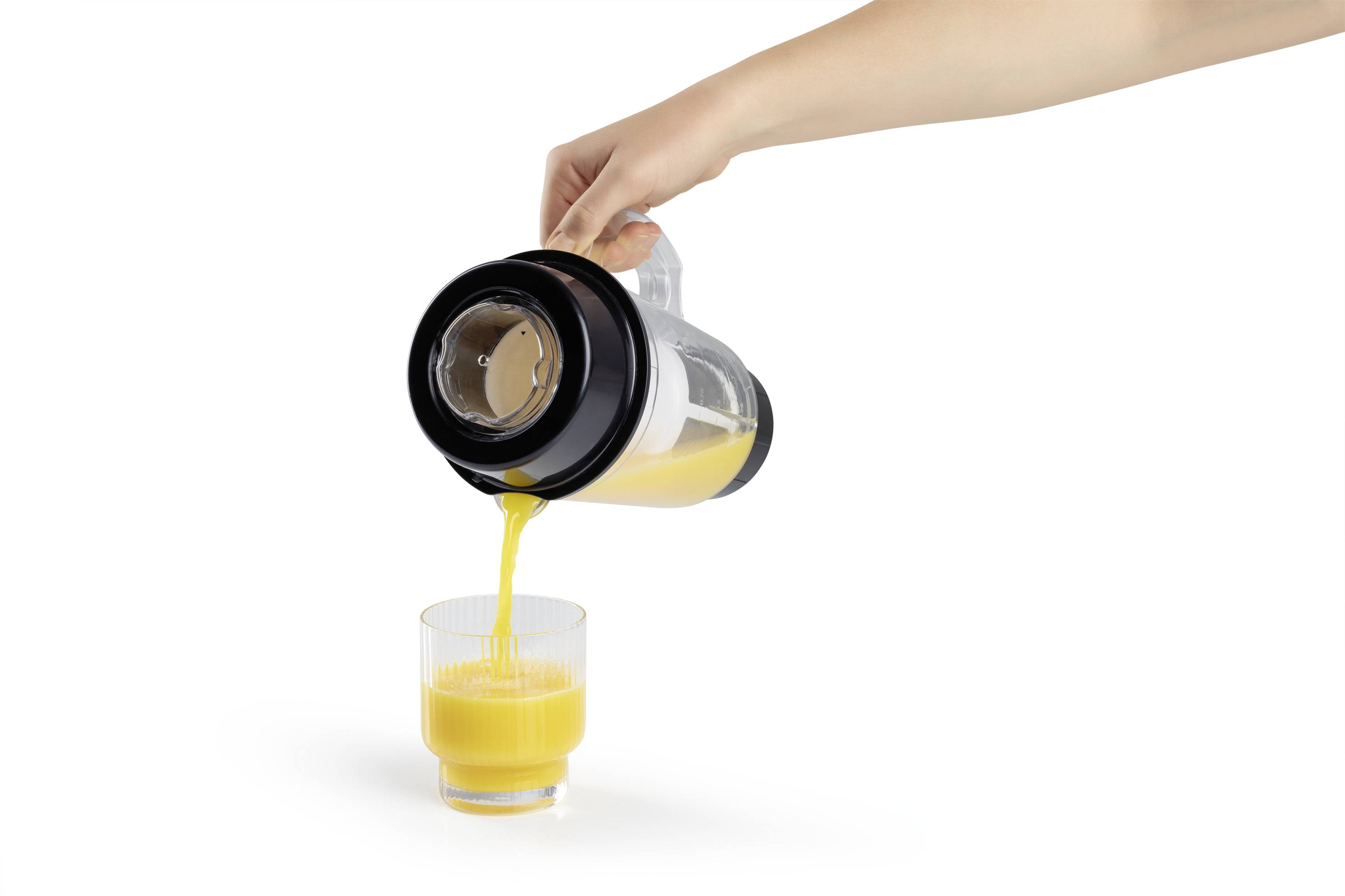 Eine Hand gießt Orangensaft aus einem Krug in ein Glas. Der Hintergrund ist weiß und schlicht.
