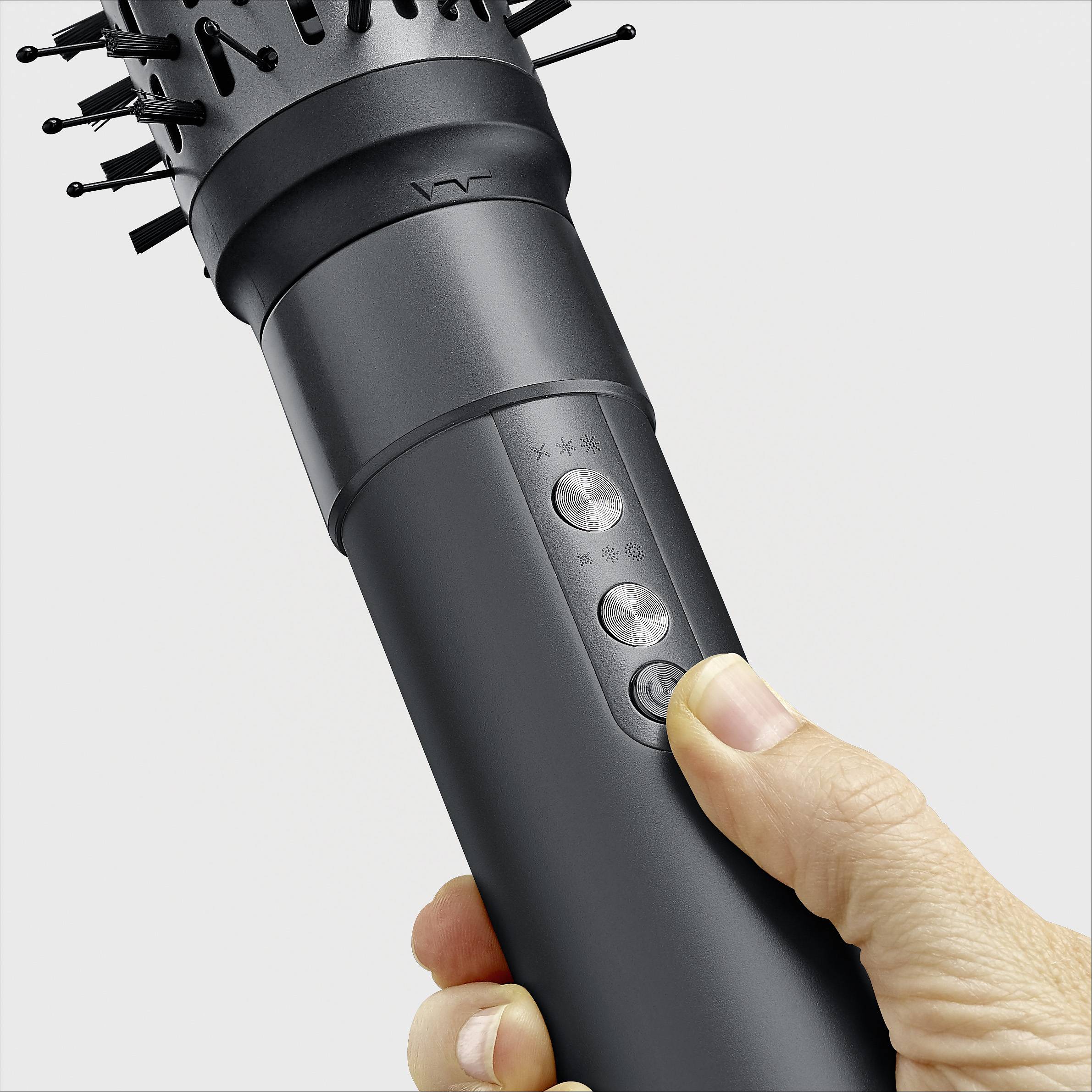 Elektronisches Haarstyling-Gerät mit verschiedenen Aufsätzen, gehalten von einer Hand, zeigt Steuerungstasten und drehbaren Kopf.