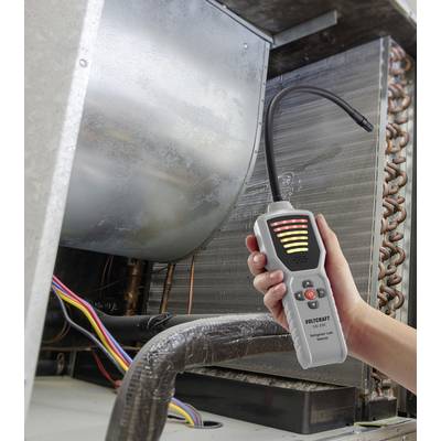 Eine Hand hält einen elektronischen Leckdetektor mit einer flexiblen Sonde in der Nähe von HVAC-Ausrüstung und zeigt Detektionsleuchten und Bedienknöpfe.