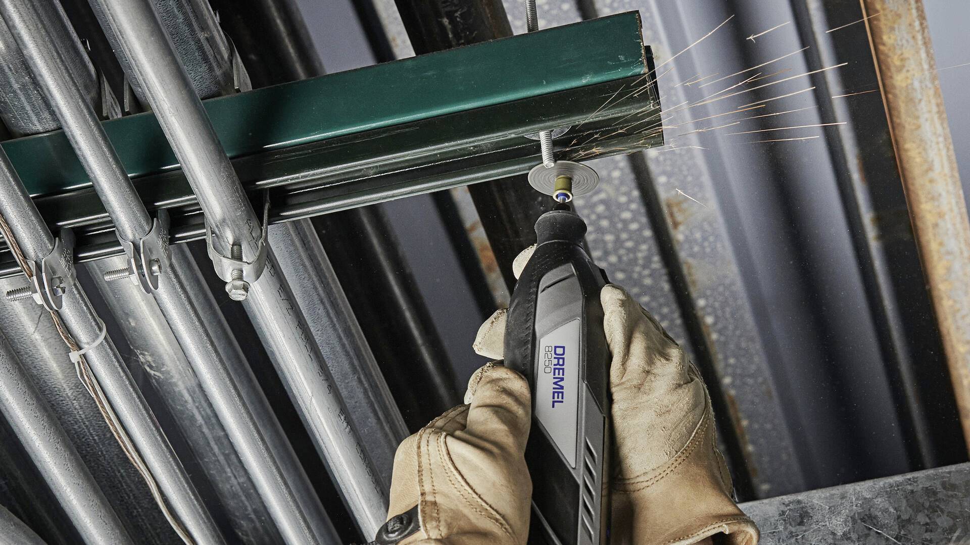 'Eine Person schneidet mit einem Dremel-Werkzeug ein Metallrohr. Funken fliegen. Trägt Arbeitshandschuhe für Sicherheit.'