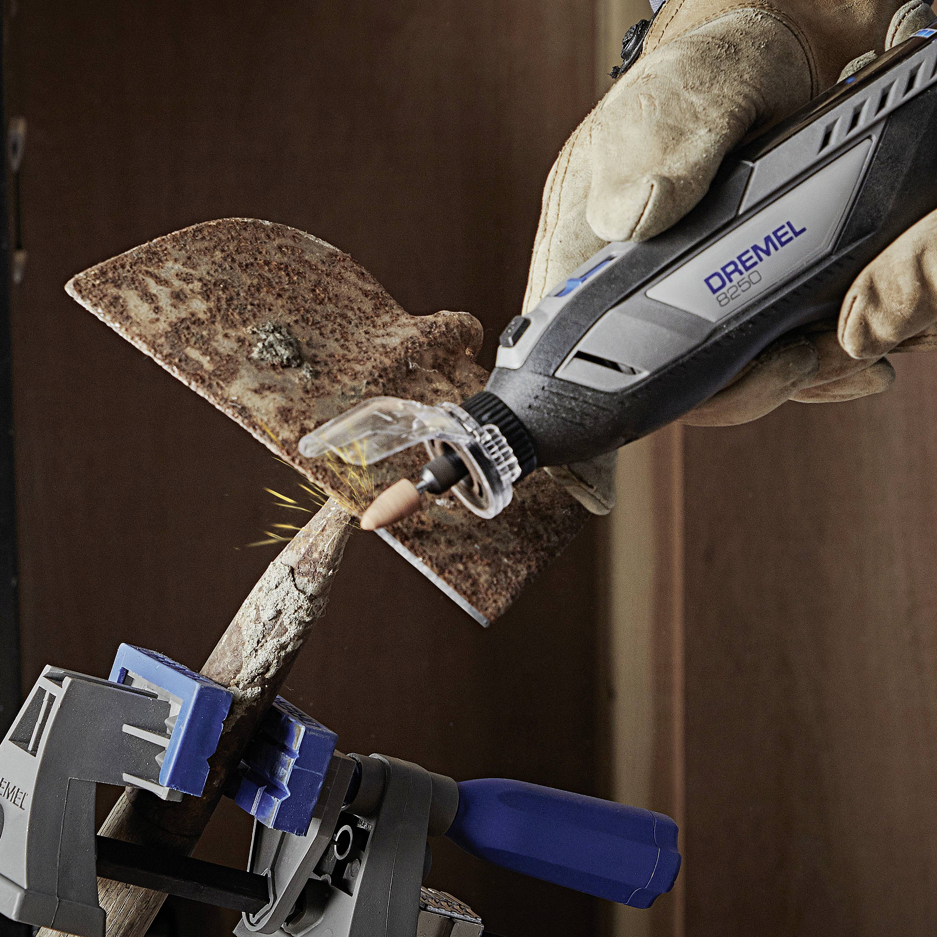 Eine Person arbeitet mit einem Dremel-Werkzeug an einem Metallstück. Funken fliegen bei der Bearbeitung, während das Metall in einem Schraubstock fixiert ist.