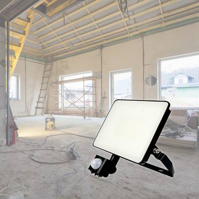 Baustelle im Innenraum mit hellem Baustrahler im Vordergrund; Gerüst und Leitern im Hintergrund; leere, unfertige Räume.