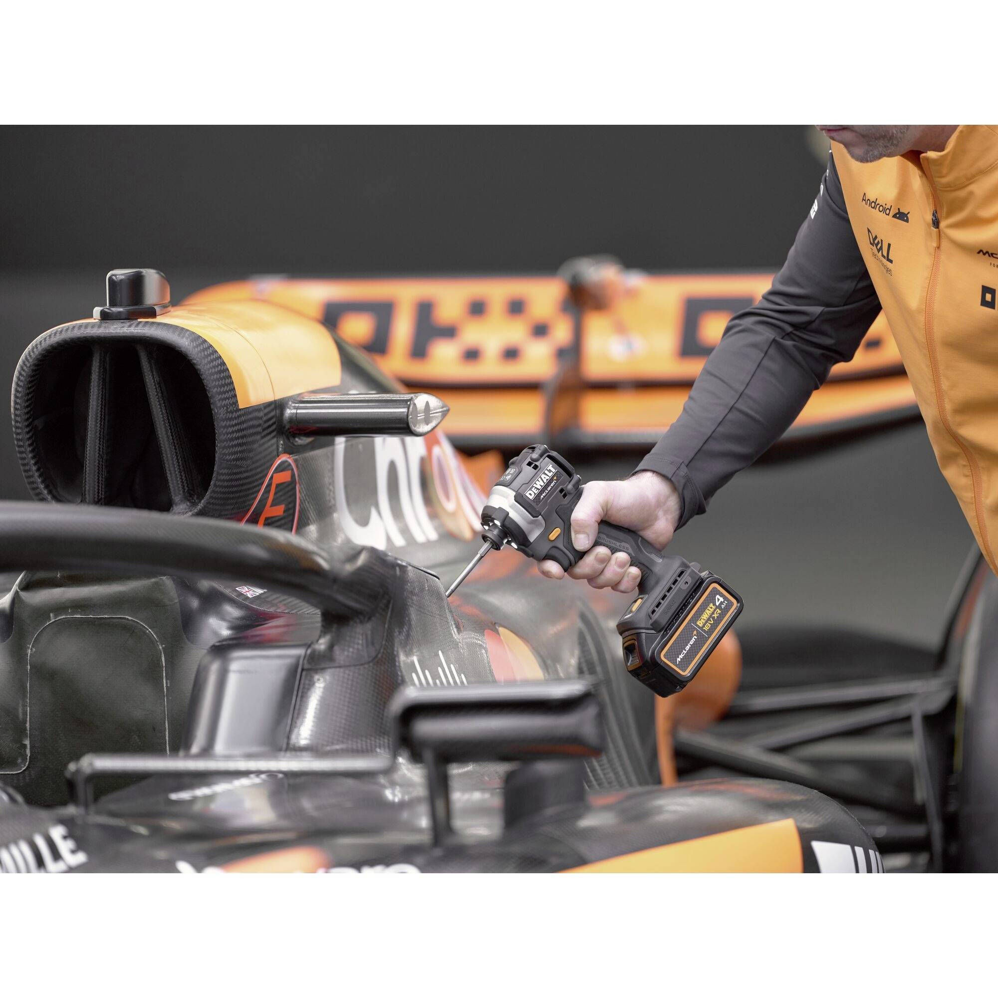 Ein Mechaniker arbeitet mit einem Elektrowerkzeug an der Verkleidung eines Formel-1-Autos in der Garage.
