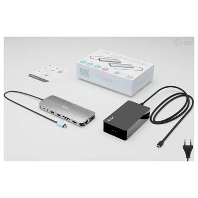 USB-C-Dock: Silbernes, rechteckiges Gerät mit mehreren Anschlüssen, verbunden mit schwarzem Netzkabel. Verpackung und Anleitung im Hintergrund.
