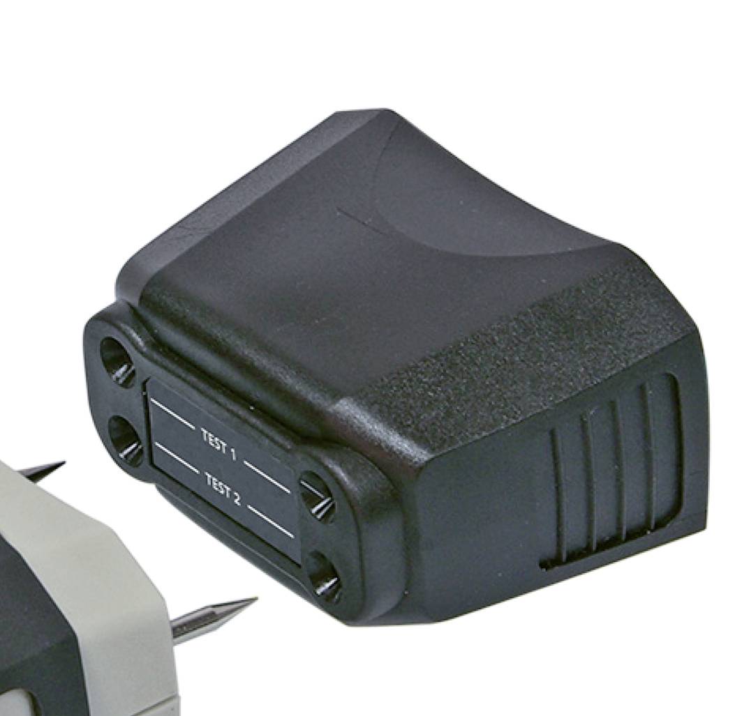 Ein schwarzer, abnehmbarer Adapter-Aufsatz, der auf ein elektronisches Gerät gesteckt werden kann. Enthält Beschriftungen 'TEST 1' und 'TEST 2'.