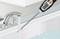 Ein digitales Thermometer misst die Wassertemperatur im Waschbecken mit fließendem Wasser. Das Display zeigt 39,5°C an.