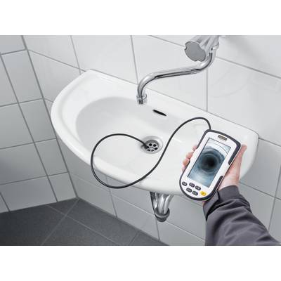 Eine Person hält ein Endoskop mit Monitor über einem Waschbecken. Auf dem Bildschirm ist das Abflussrohr zu sehen, um Blockaden zu prüfen.