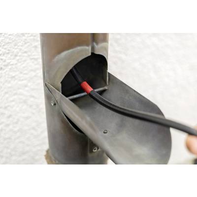 Ein rohrförmiges Metallobjekt, das ein schwarzes, rot markiertes Kabel enthält, das durch eine Öffnung verläuft.
