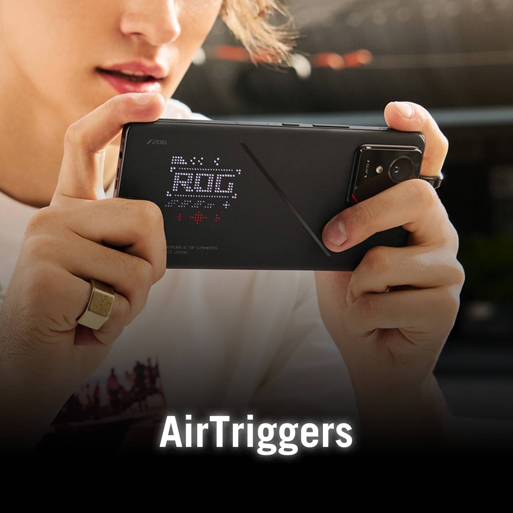 Person hält ein Smartphone mit 'ROG' auf der Rückseite. Der Text 'AirTriggers' ist unten sichtbar.