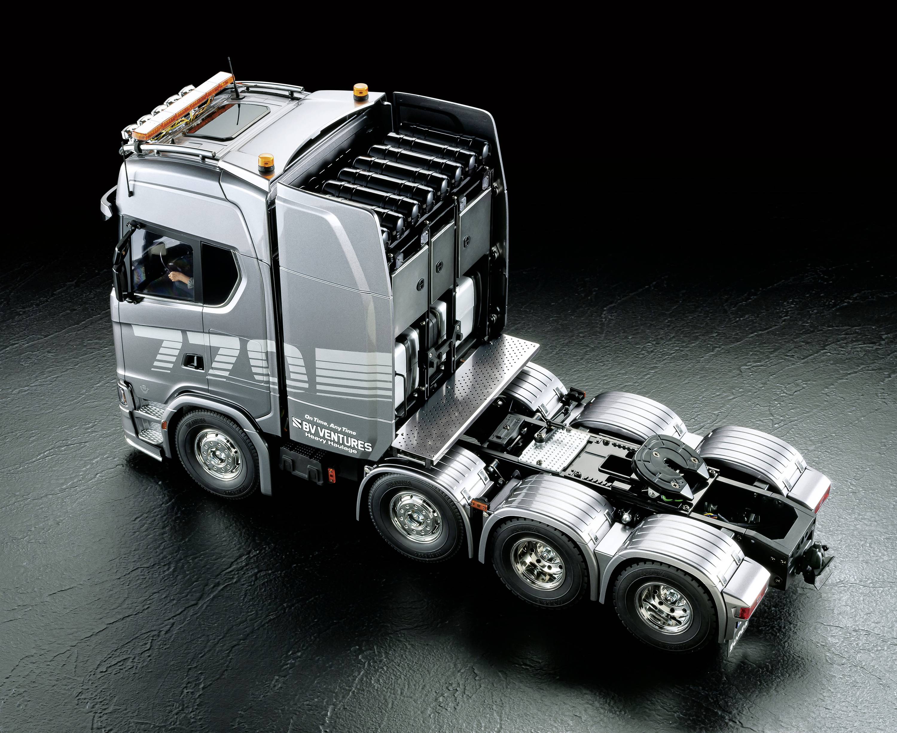 Silberner Lastwagen ohne Anhänger auf dunklem Hintergrund, zeigt Fahrzeugdetails und technisches Design.