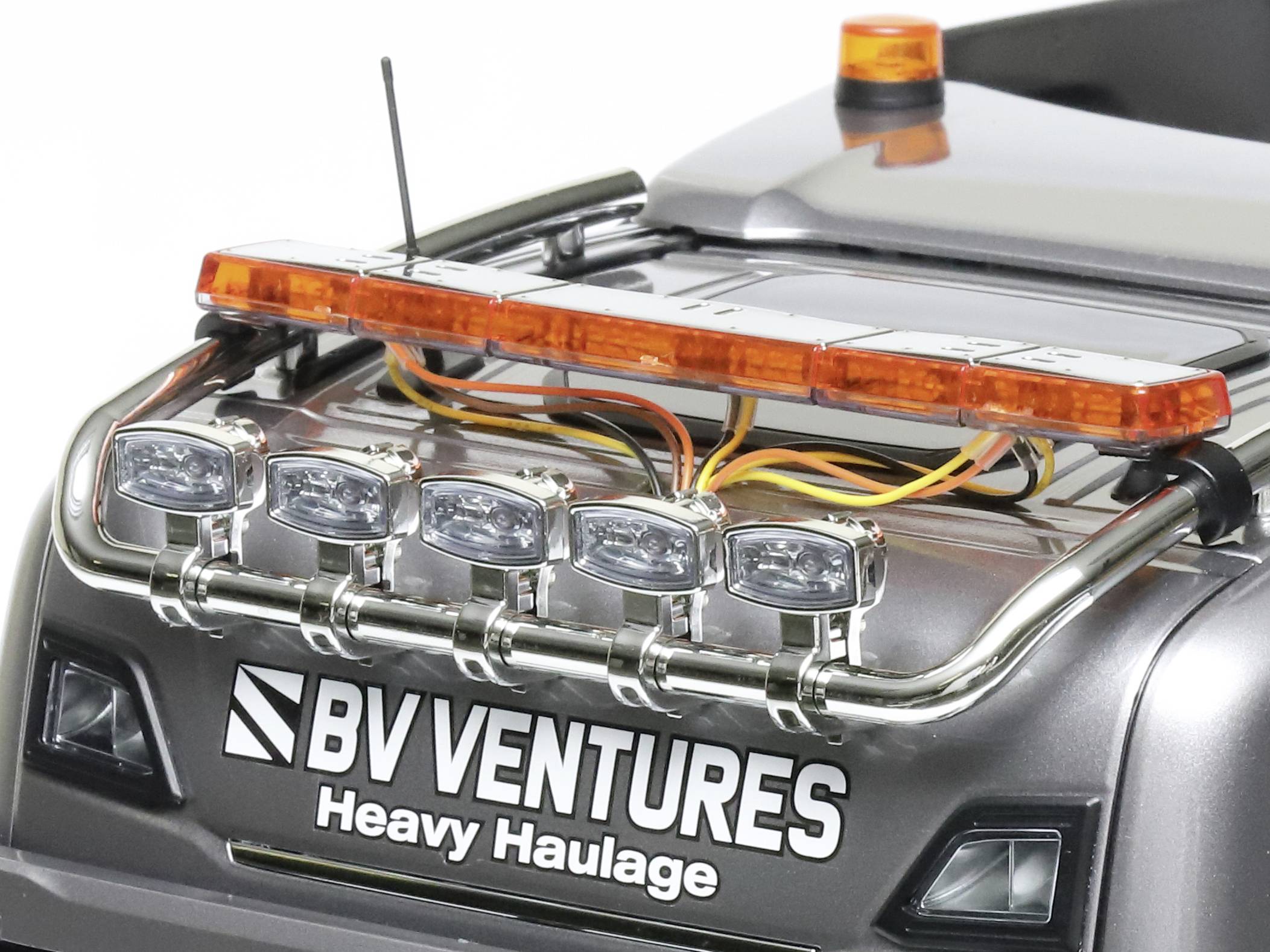 Ein Modellfahrzeug mit orangefarbenen Warnleuchten und Aufschrift 'BV Ventures Heavy Haulage' auf dem Heck.