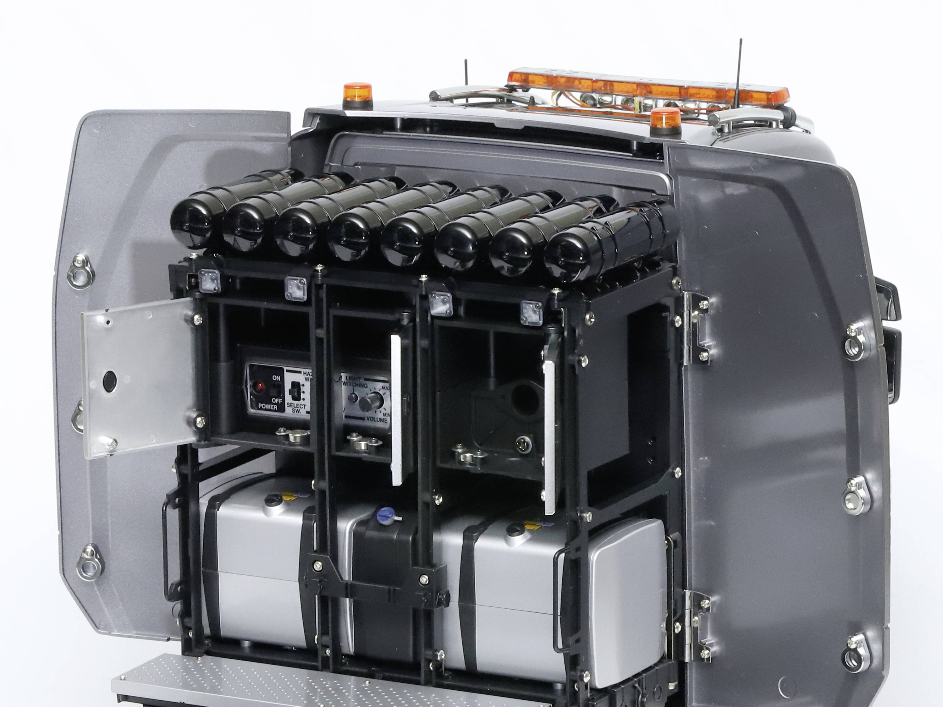 Ein graues Fahrzeug mit geöffneter Rückseite zeigt mehrere zylindrische Behälter und elektronische Geräte, möglicherweise für technische Zwecke.