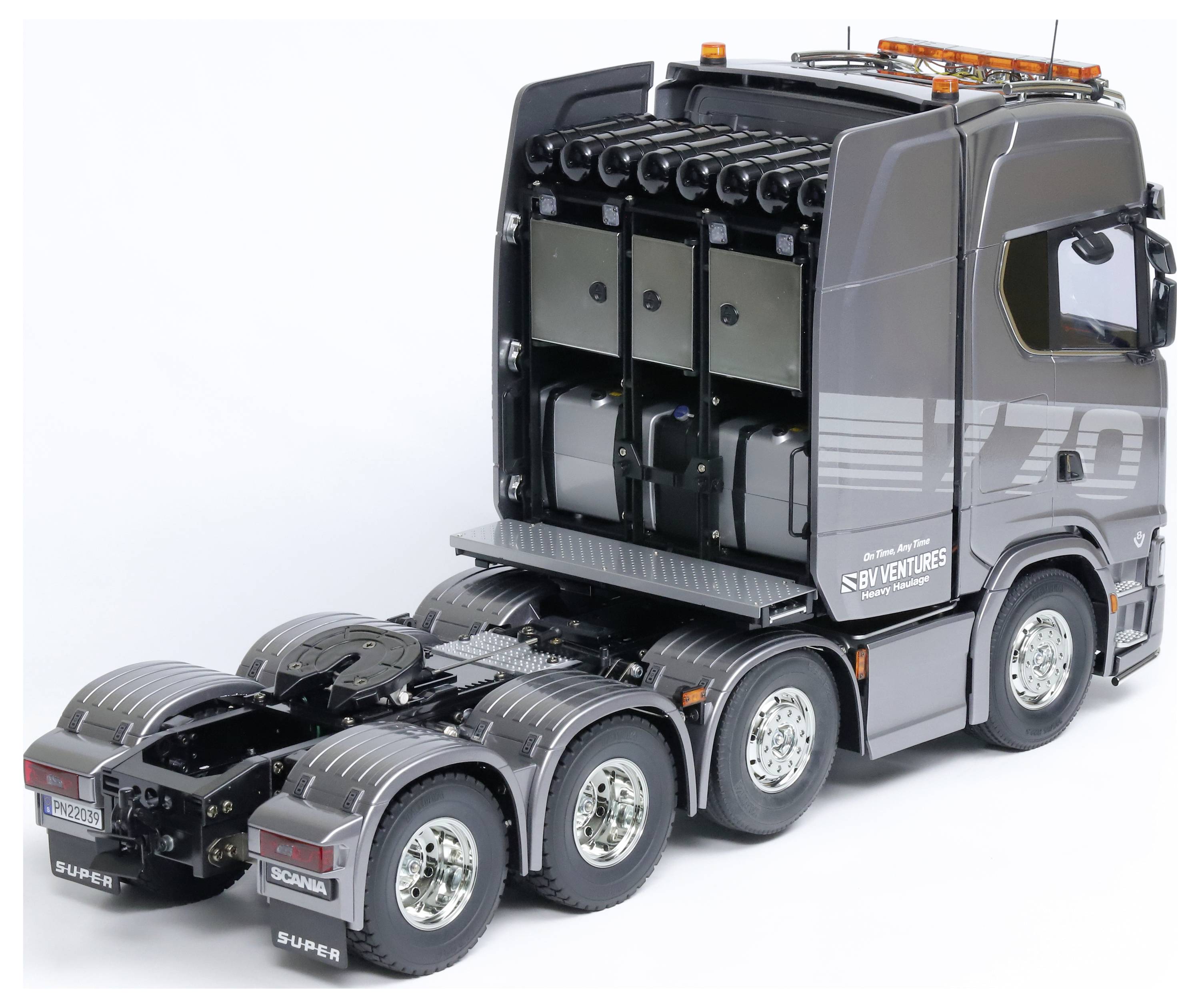 Ein grauer Modell-LKW mit mehreren Hinterachsen und orangen Warnleuchten. Seitenansicht zeigt 'S.B.VENTURES'-Aufdruck.