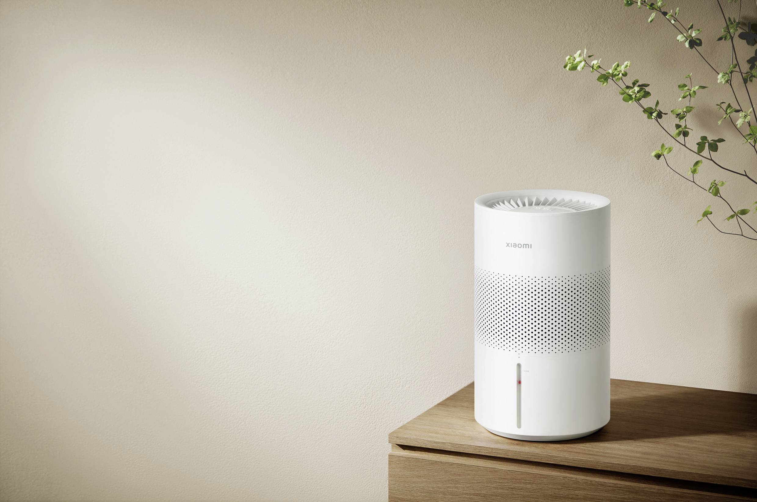 Luftreiniger auf einem Tisch mit Pflanze im Hintergrund, minimalistisches Design, beige Wand.