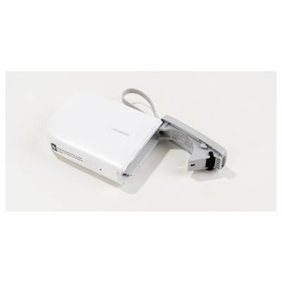 Ein weißes, tragbares Gerät mit aufklappbarem Deckel und USB-Anschluss, möglicherweise ein Etikettendrucker, liegt auf einer weißen Fläche.