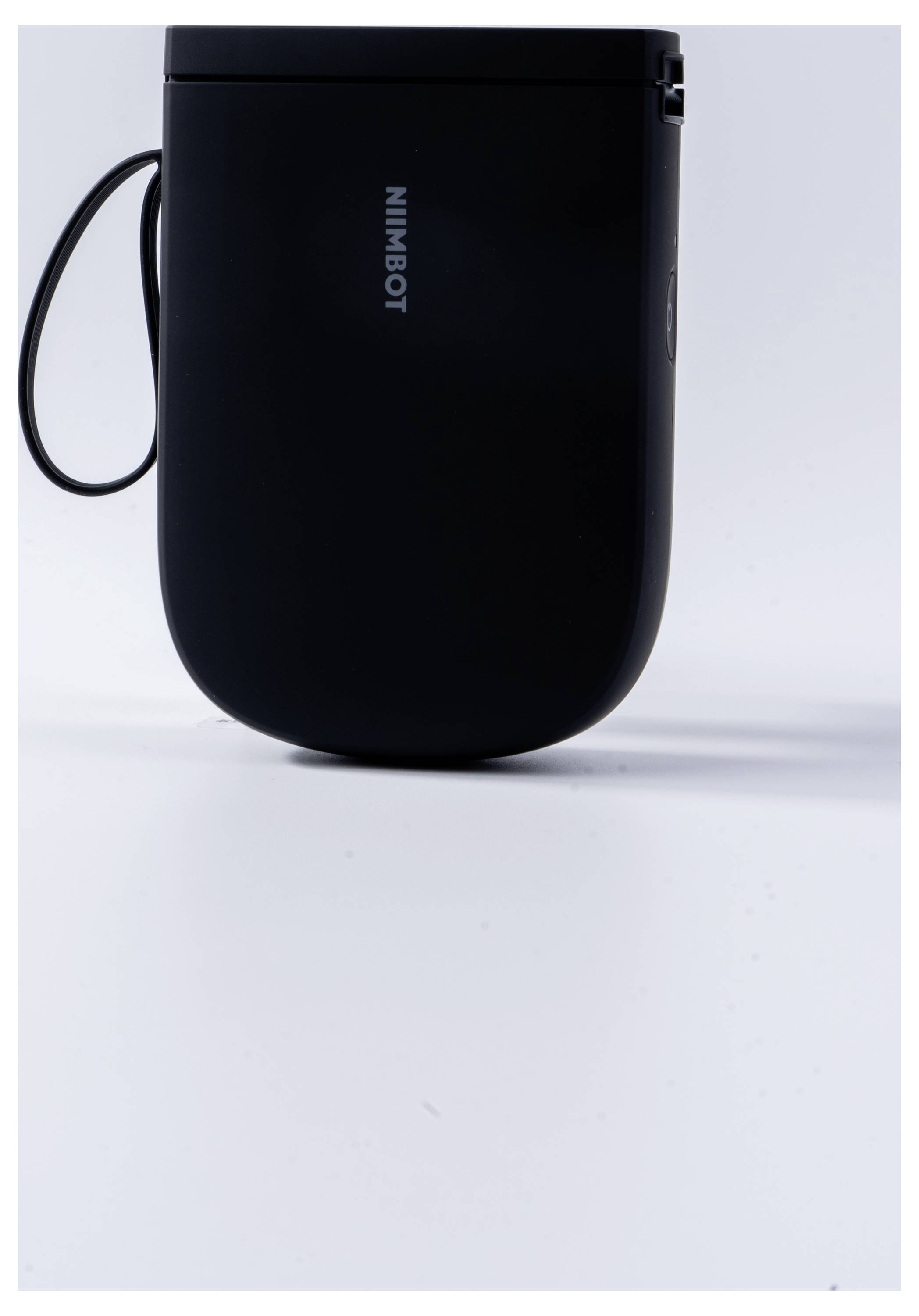 Ein schwarzes, handliches Gerät mit Trageschlaufe und der Aufschrift 'NimBot', vor einem weißen Hintergrund.
