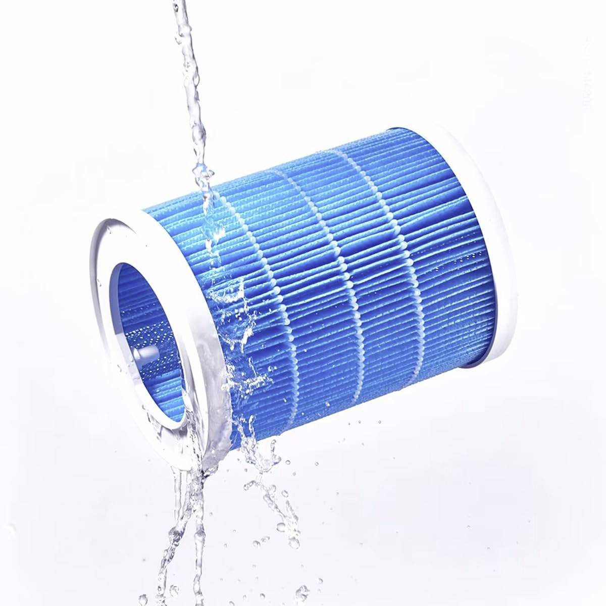 Ein blauer zylindrischer Wasserfilter, aus dem Wasser spritzt, auf weißem Hintergrund.
