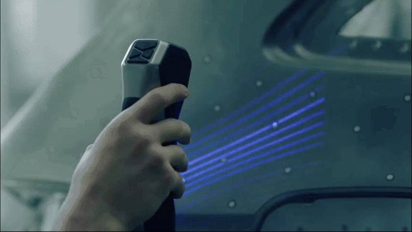 Eine Hand hält einen Steuerknüppel, während blaue Lichtstreifen über die Oberfläche eines Fahrzeugs oder Geräts verlaufen und ein moderner Technologieeinsatz angedeutet wird.