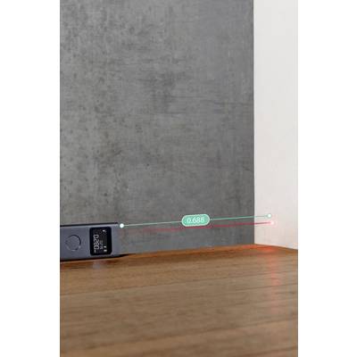 Ein digitaler Laser-Entfernungsmesser misst die Entfernung von einer Holzoberfläche zu einer Wand und zeigt einen Messwert von 0,688 auf seinem Display an.