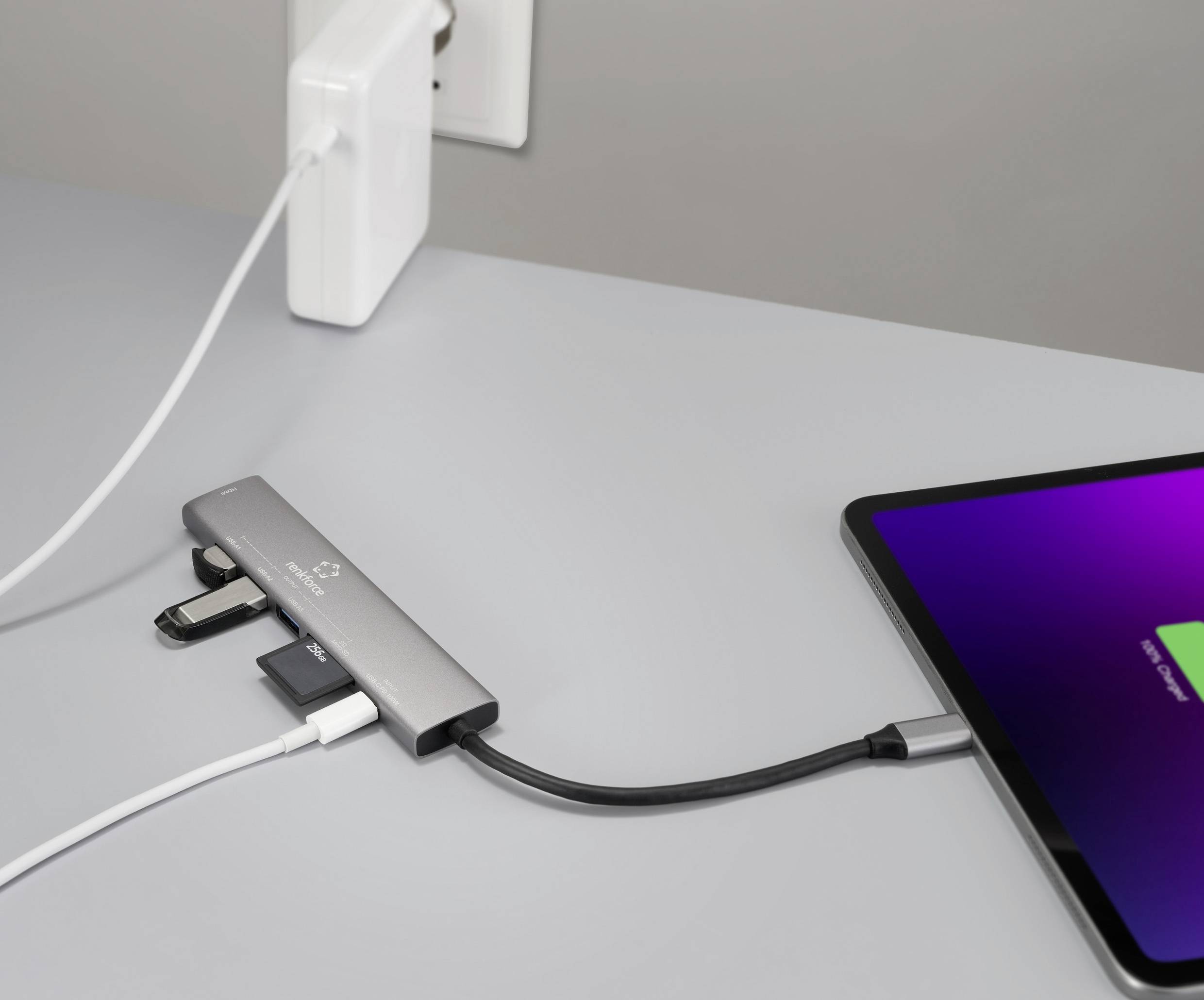 Ein Ladehub, der mit einem Tablet und einer Steckdose verbunden ist, mit mehreren Geräten, die in seine Anschlüsse eingesteckt sind.