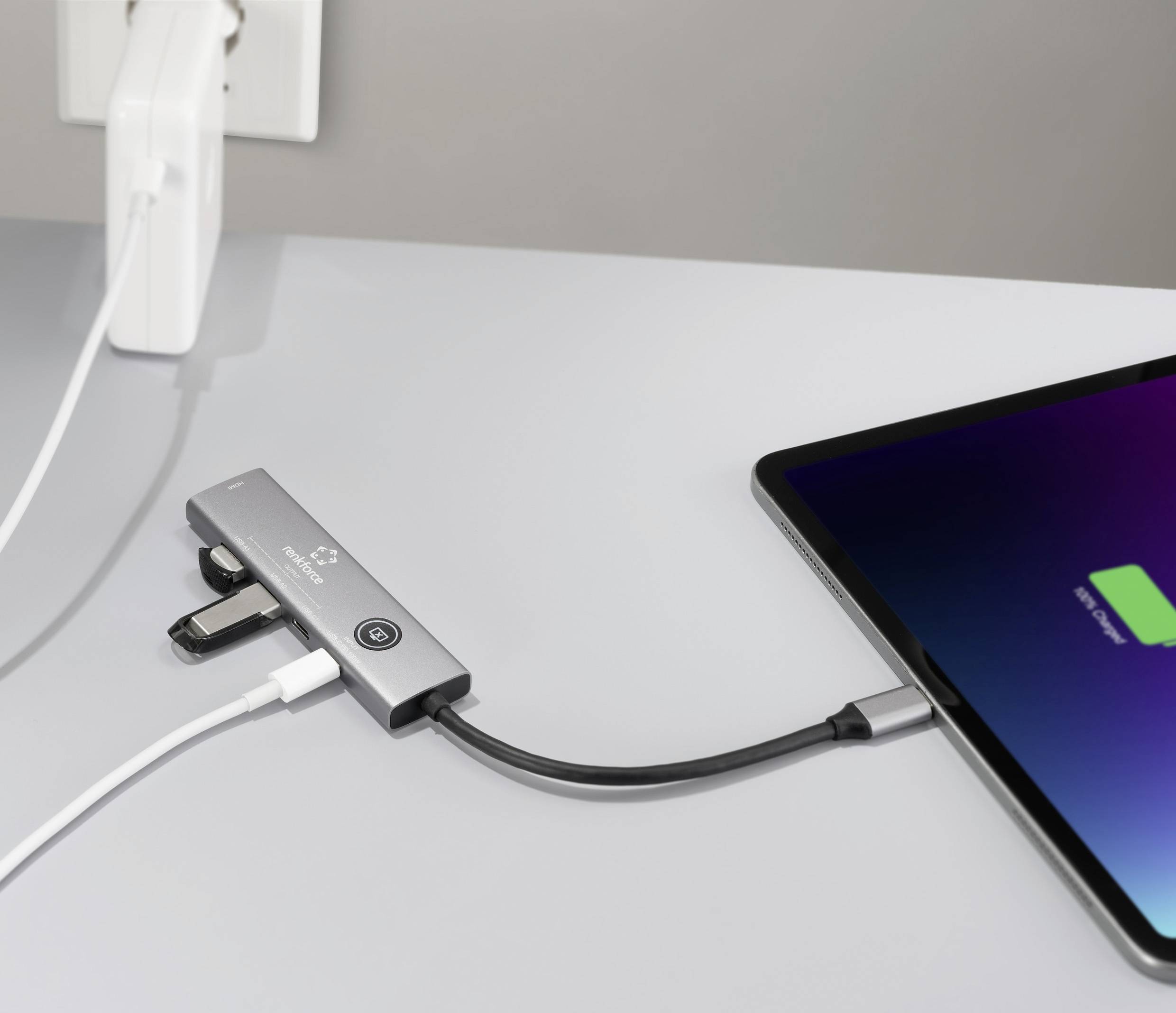 Ein Tablet, das mit einem Multi-Port-Adapter verbunden ist, welcher an eine Stromquelle angeschlossen ist, zeigt das Laden durch ein Ladesymbol auf dem Bildschirm an.