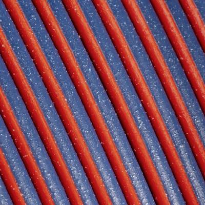 Nahaufnahme von rot und blau gestreiften Bahnen, die diagonal verlaufen. Die Textur wirkt körnig und reflektiert Licht.