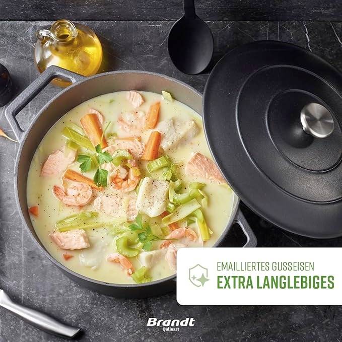 Ein schwarzer Topf mit Lachs, Garnelen, Sellerie und Möhren in einer hellen Sauce; 'Emailliertes Gusseisen, extra langlebiges'.