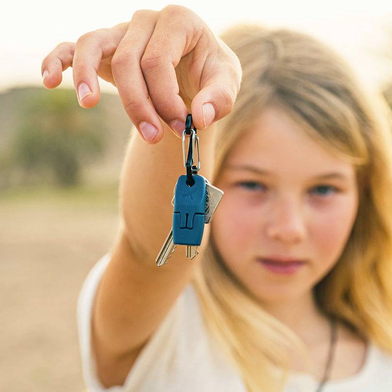 Ein Kind hält einen Schlüsselanhänger mit mehreren Schlüsseln in die Kamera, Hintergrund ist leicht verschwommen.
