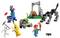 Eine bunte Lego-Szene mit Figuren: ein Skelett mit Spitzhacke, eine Bananenfigur, ein Mensch mit Fackel, ein Dino, eine Lamafigur und ein Lagerfeuerset.
