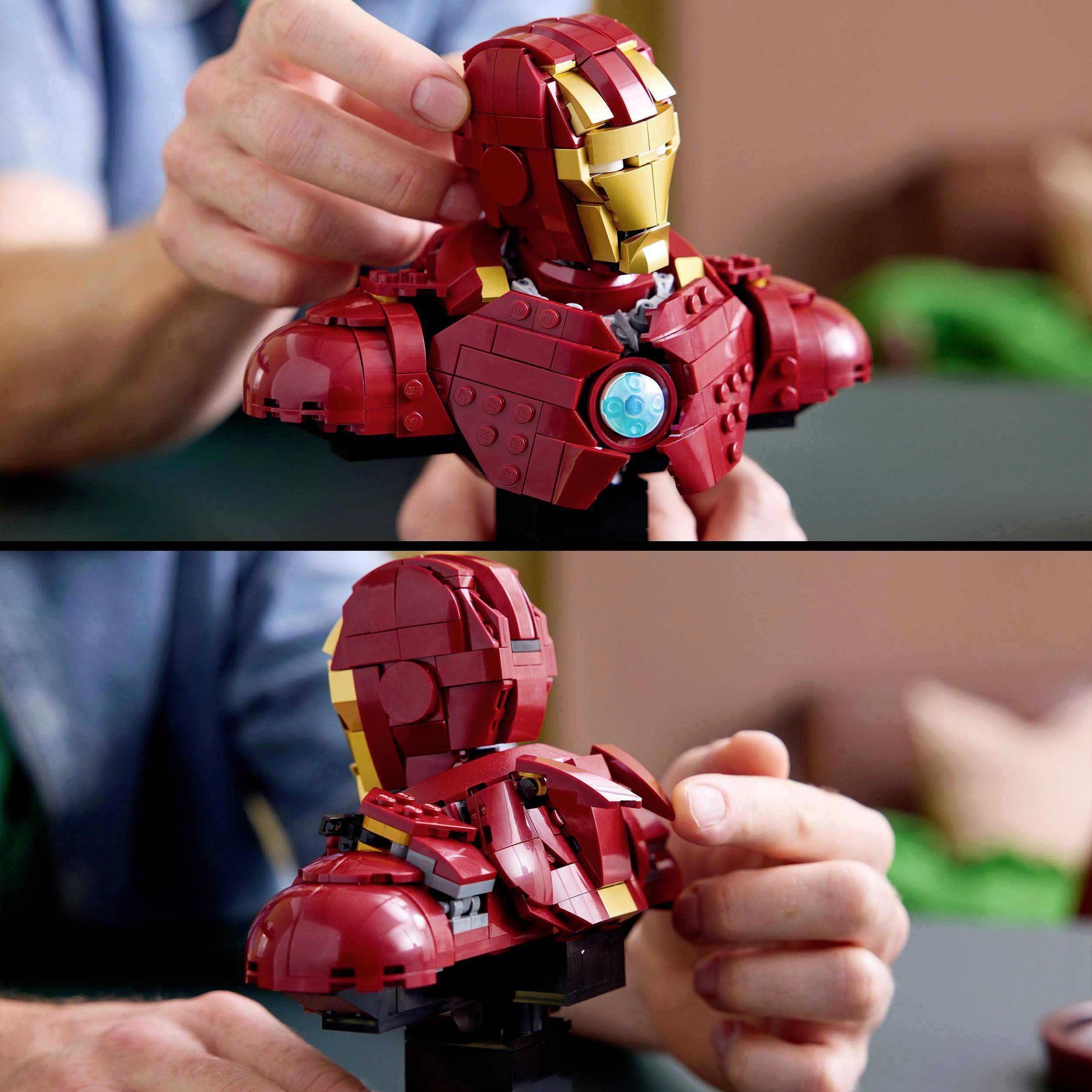 Eine Person hält ein Lego-Modell eines roten und goldenen Superhelden-Anzugs. Hände positionieren Teile des Modells.