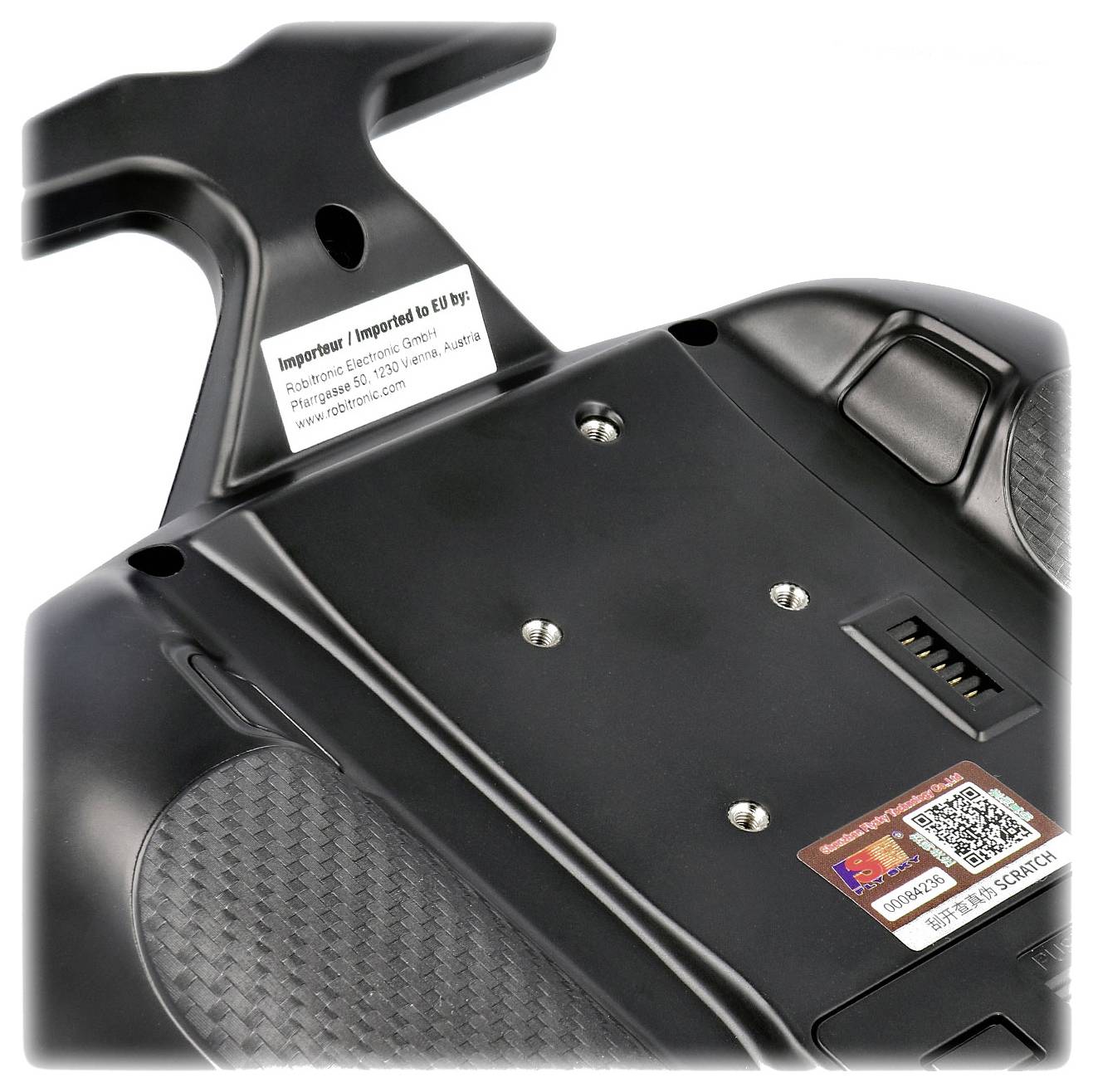 Unterseite eines elektronischen Geräts mit Etiketten, Schrauben und einem Batteriefach. Text auf Etiketten erwähnt Herstellerangaben.