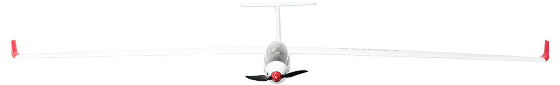 Ein weißes Segelflugzeug mit einem schwarzen Propeller und roten Flügelspitzen fliegt direkt auf den Betrachter zu.