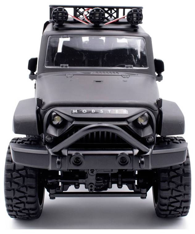 Schwarzer Geländewagen mit robustem Design und großen Reifen, aufgenommen von vorne. Dachträger mit Scheinwerfern sichtbar.