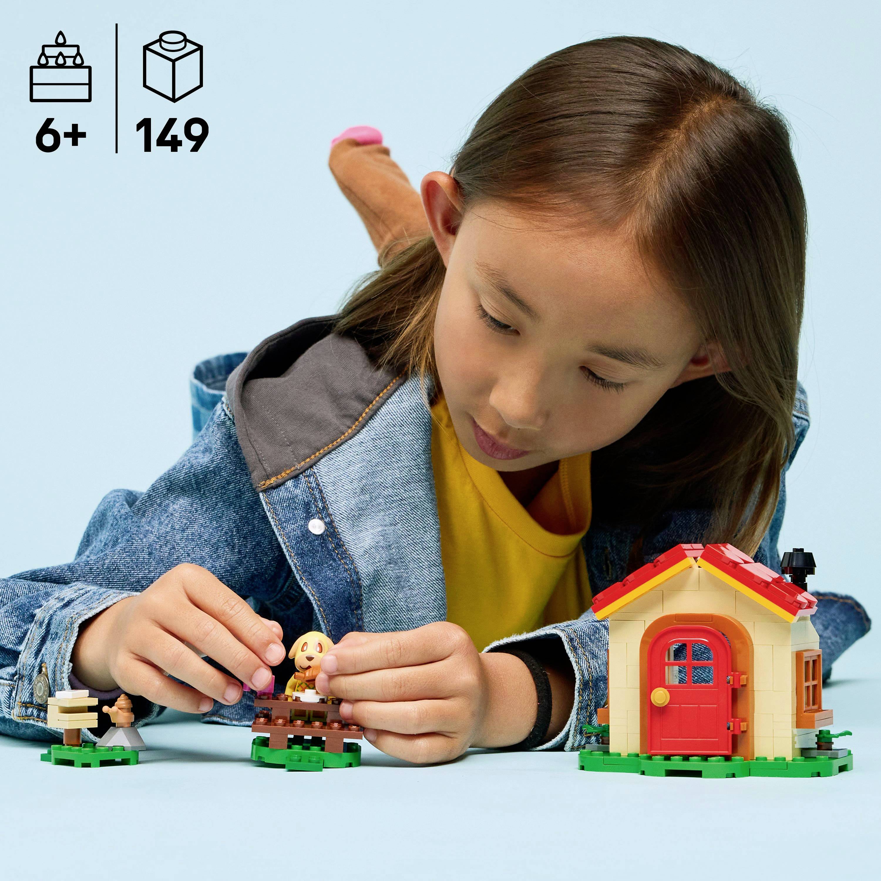 Ein Kind spielt mit einem Spielzeugset, das ein kleines Haus und Figuren enthält. Oben links ist '6+' und '149' zu sehen, was das Alter und die Stückzahl anzeigt.