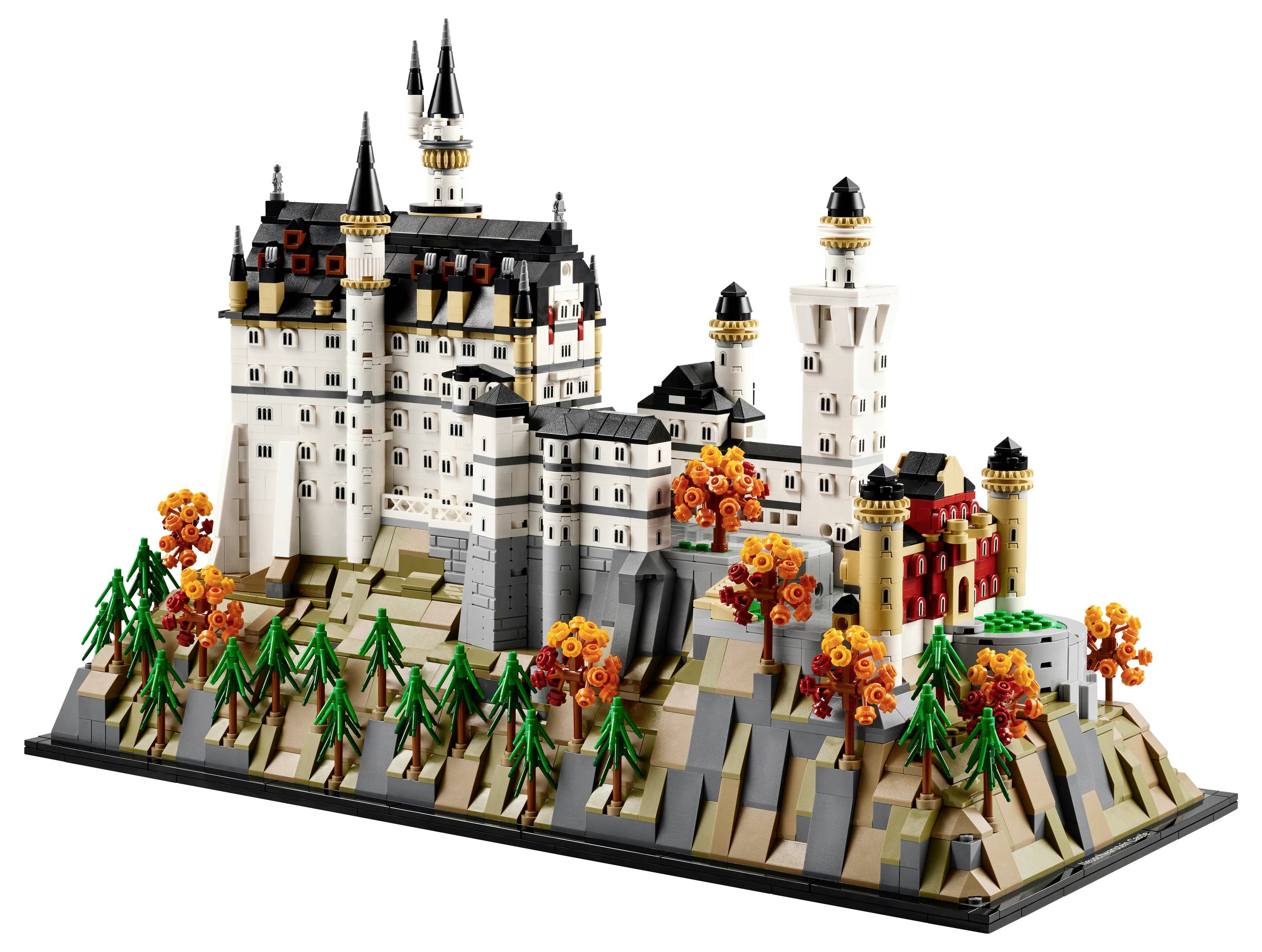 Ein detailliertes LEGO-Modell eines historischen Schlosses mit mehreren Türmen, umgeben von Bäumen und herbstlich gefärbtem Laub auf einer felsigen Basis.